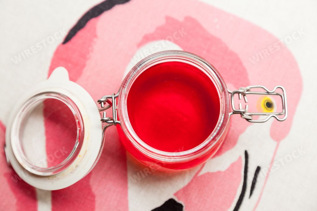A top view shot glass jar with a lid full of rose liquid in the background of the flamingo drawing