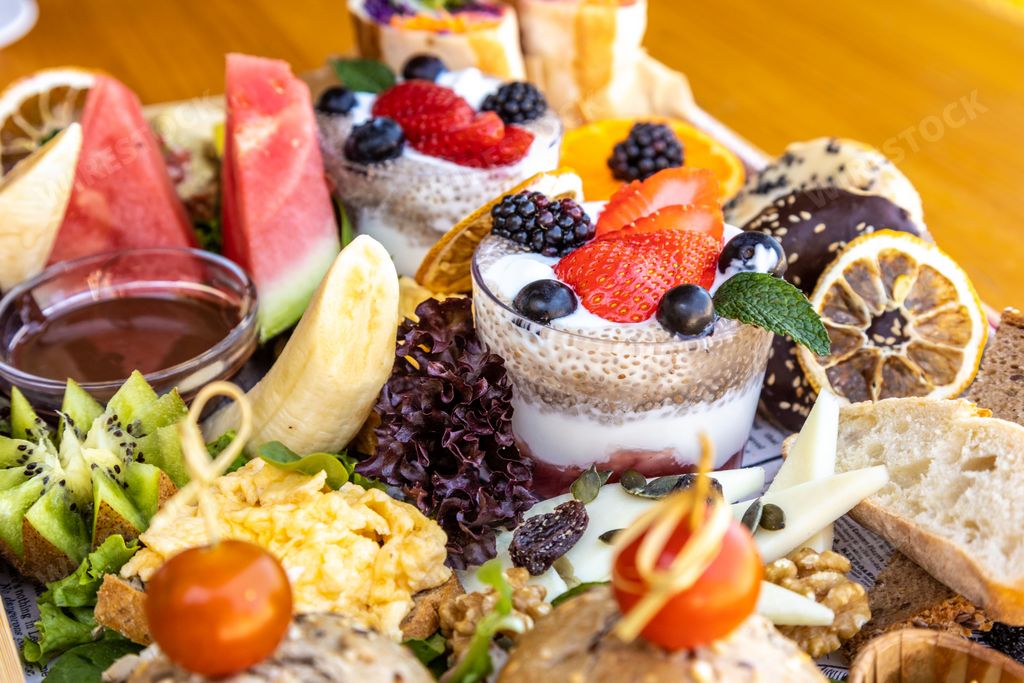 A closeup of assorted fruits, cheese, bread, and dessert on a platter