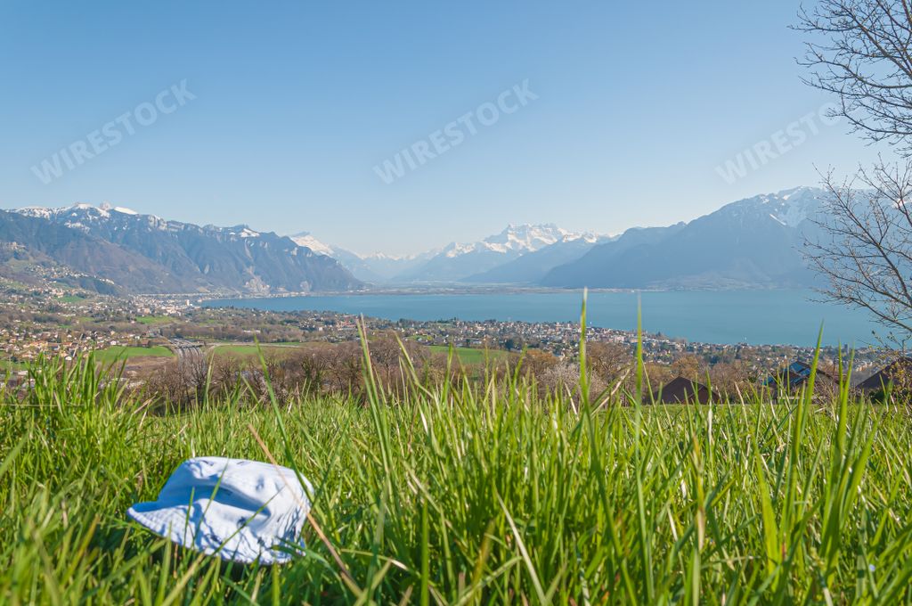 A blue hat on the grass with a peaceful view of the Geneva lake and Montreux under the swiss alps, Switzerland