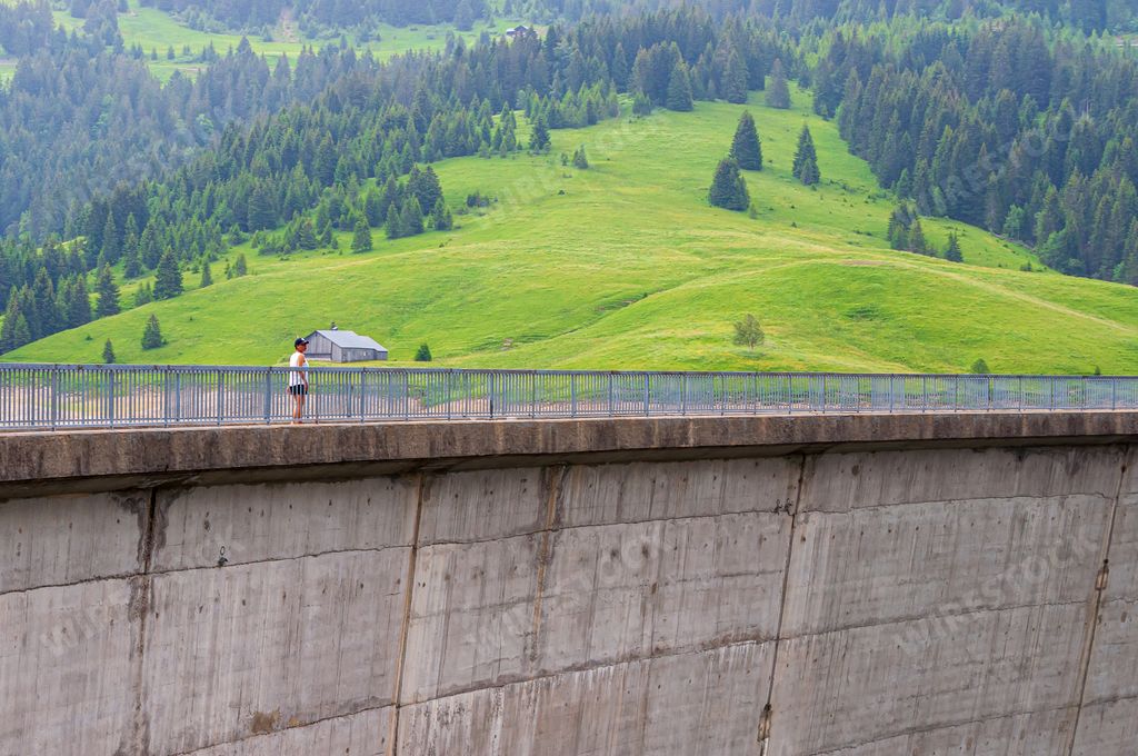 A woman near the railings of a dam of Longrin in La Lecherette on a sunny day