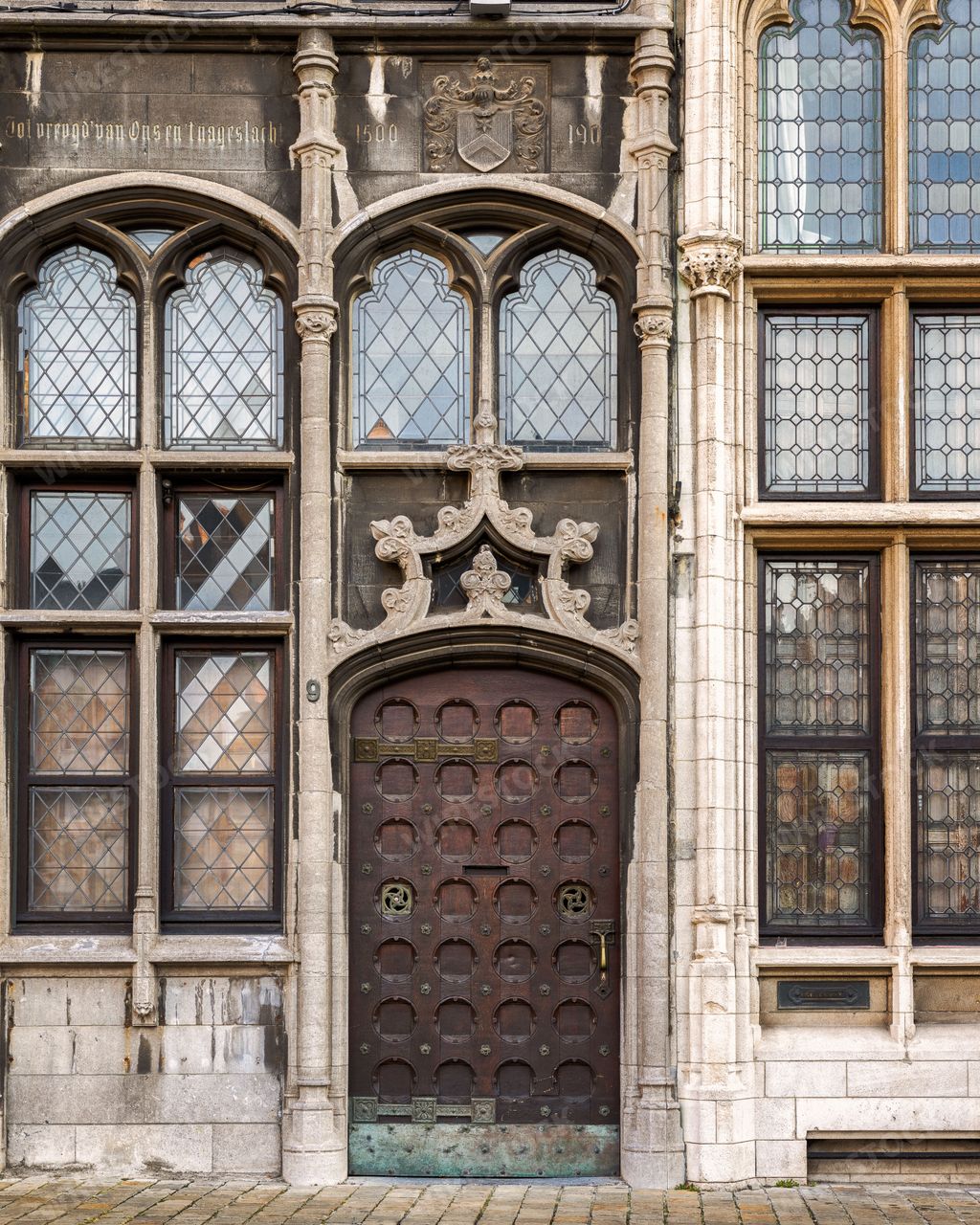 A brown wooden door leading to an old building with windows in Grote Markt, Antwerp, Flanders, Belgium