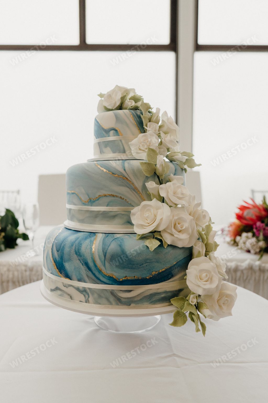 Large wedding cake decorated with white roses and blue frosting
