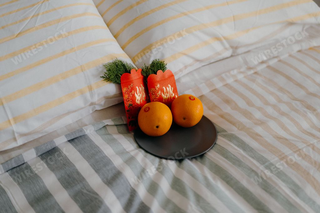 An Asian Chinese wedding ceremony with a red packet of oranges on a bed