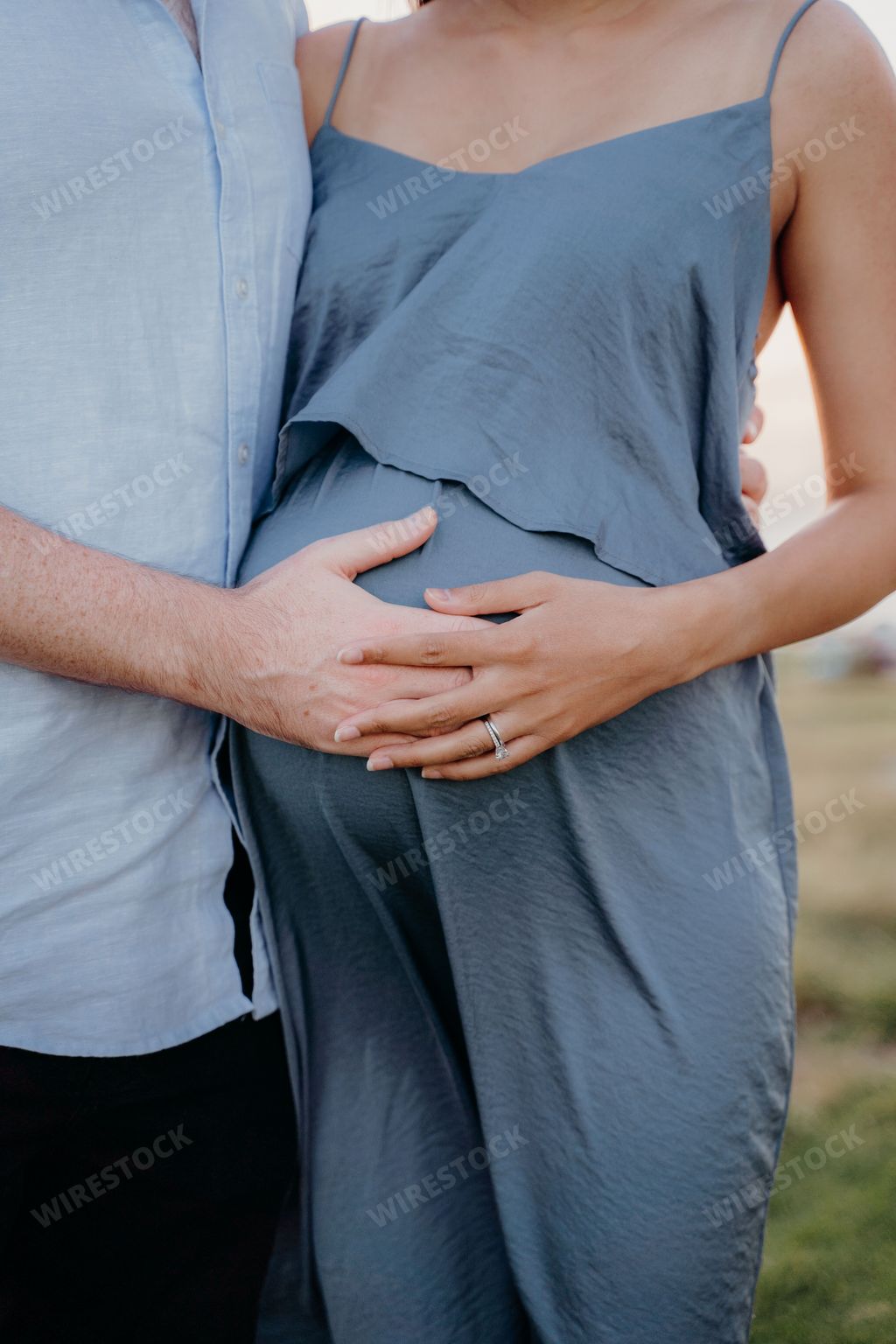 A vertical closeup shot of a husband and pregnant wife posing together at a maternity shoot