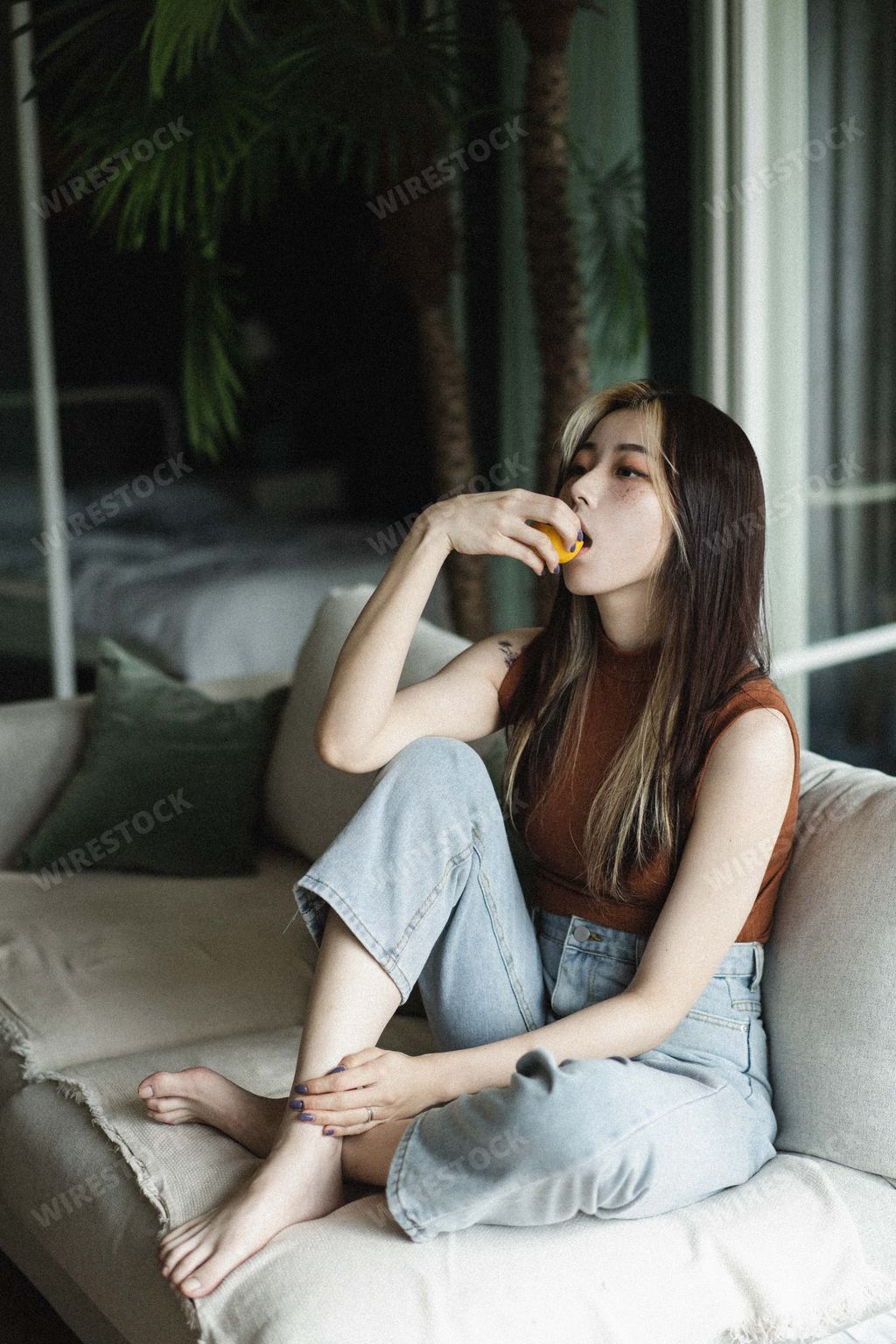 A young South Korean female with lemon in her hand sitting on the sofa at home