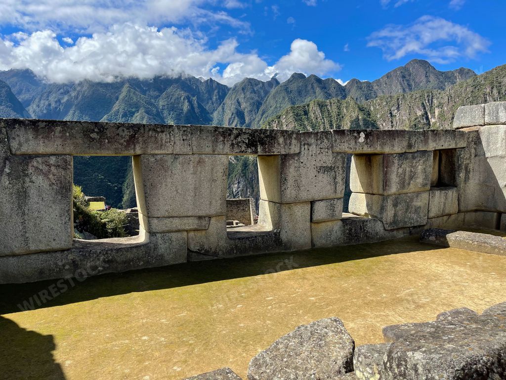 Ancient ruins of the Temple of Three Windows in Machu Picchu, with a dramatic backdrop of mountains and clouds