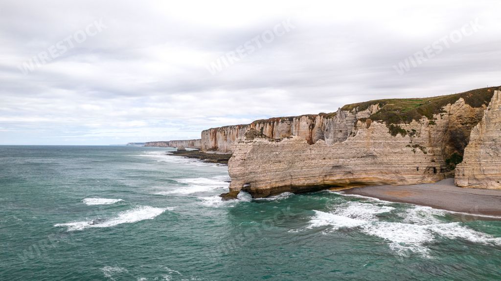 Stormy day at Etretat beach, France, showcasing the blue water and steep coast, with rough sea and dramatic views.