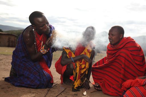 Shallow focus shot of three African males making fire Stock photo ...