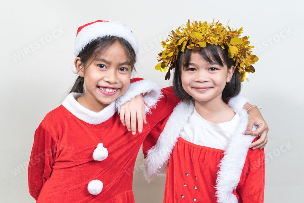 Little cute Thai girls with Santa costumes and Christmas head garland on a white background.