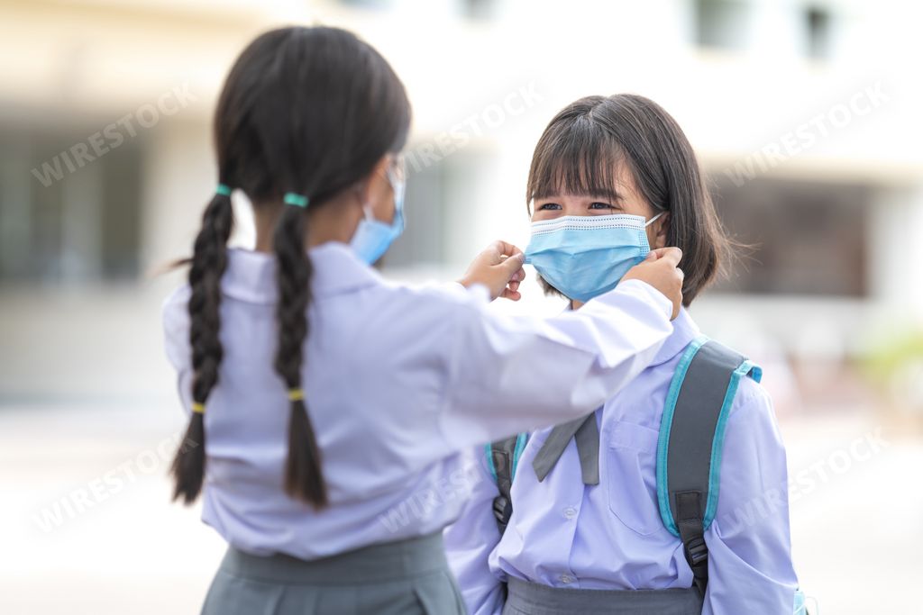 A girl helping her friend wearing a medical mask