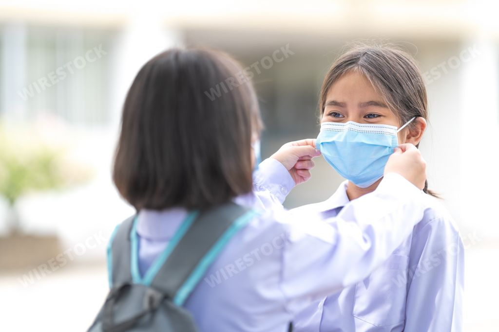 A girl helping her friend wearing a medical mask