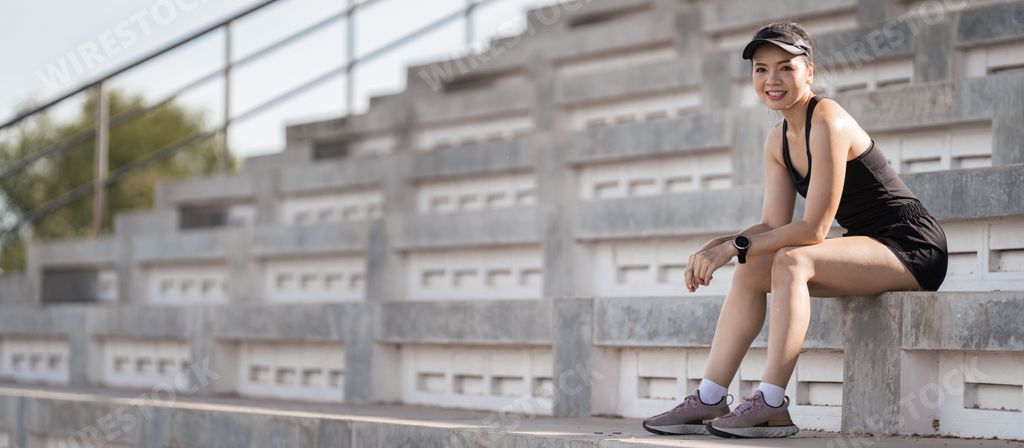 A healthy adult Asian female running up on concrete stairs of the city stadium