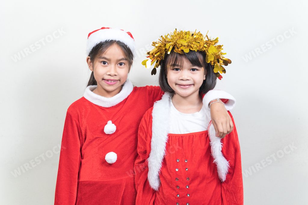 Little cute Thai girls with Santa costumes and Christmas head garland on a white background.