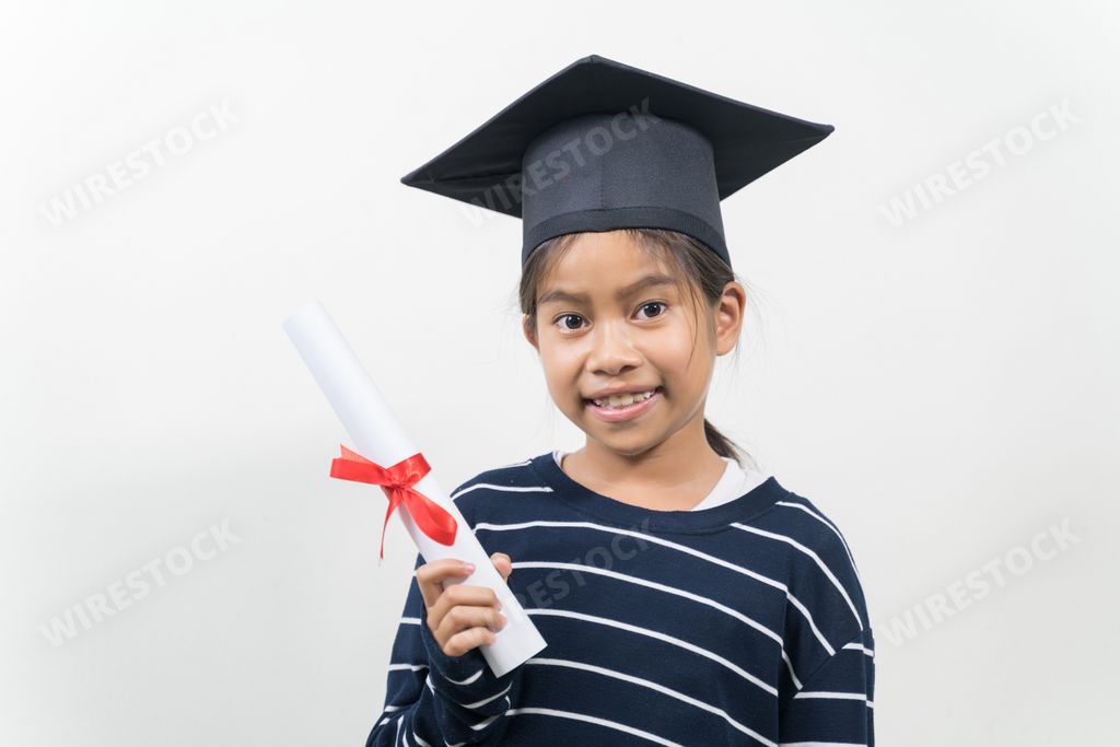 A happy Thai kid with a graduation hat and diploma isolated on white background
