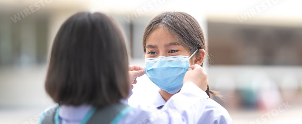 A girl helping her friend wearing a medical mask