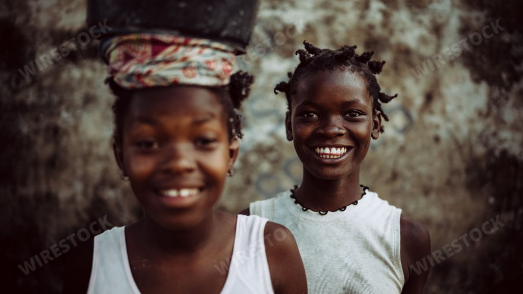 The beautiful two black beautiful girls carrying a water bowl and smiling to camera in Mozambique