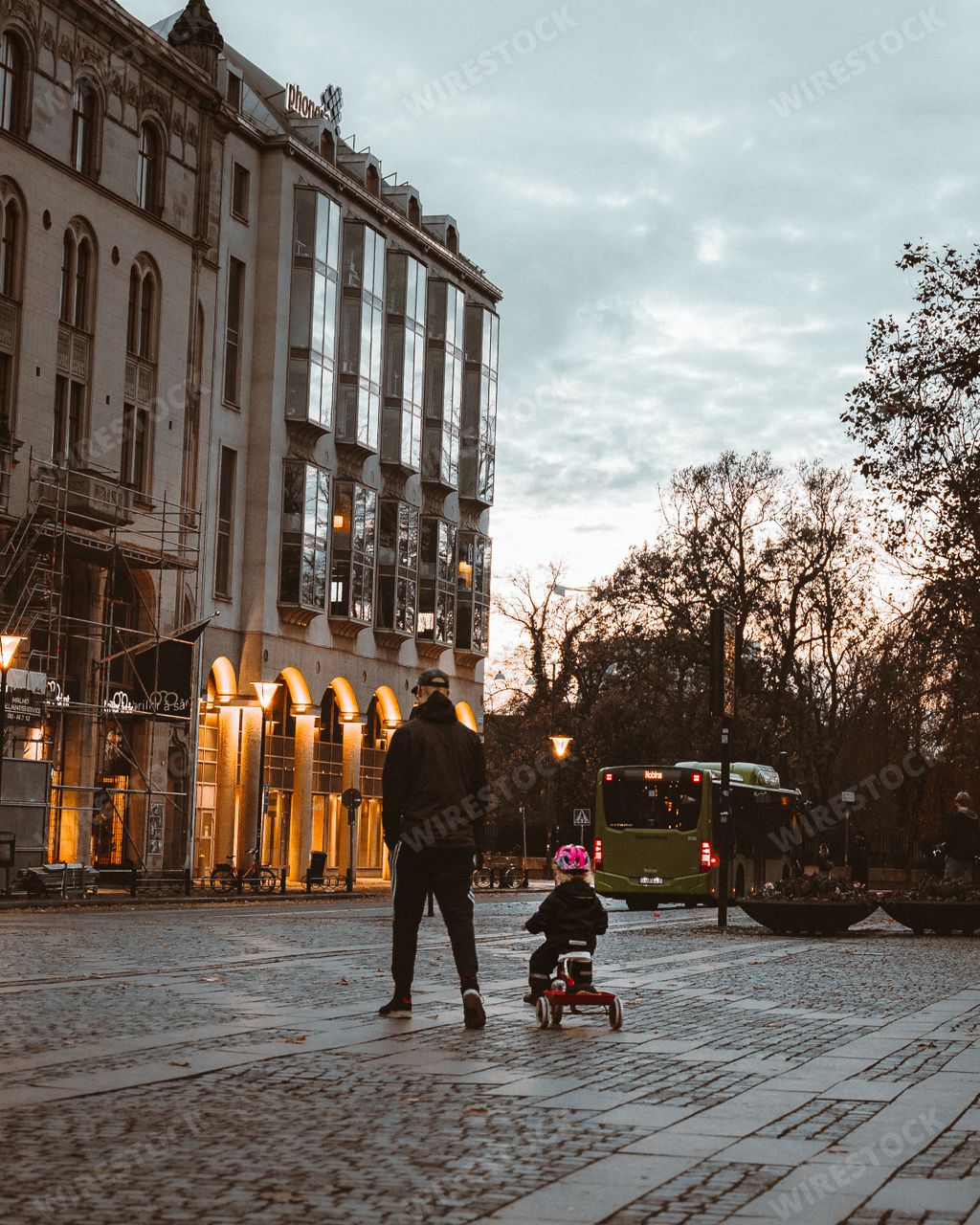 A young father walking with his son riding a tricycle in the streets of Malmo, Sweden
