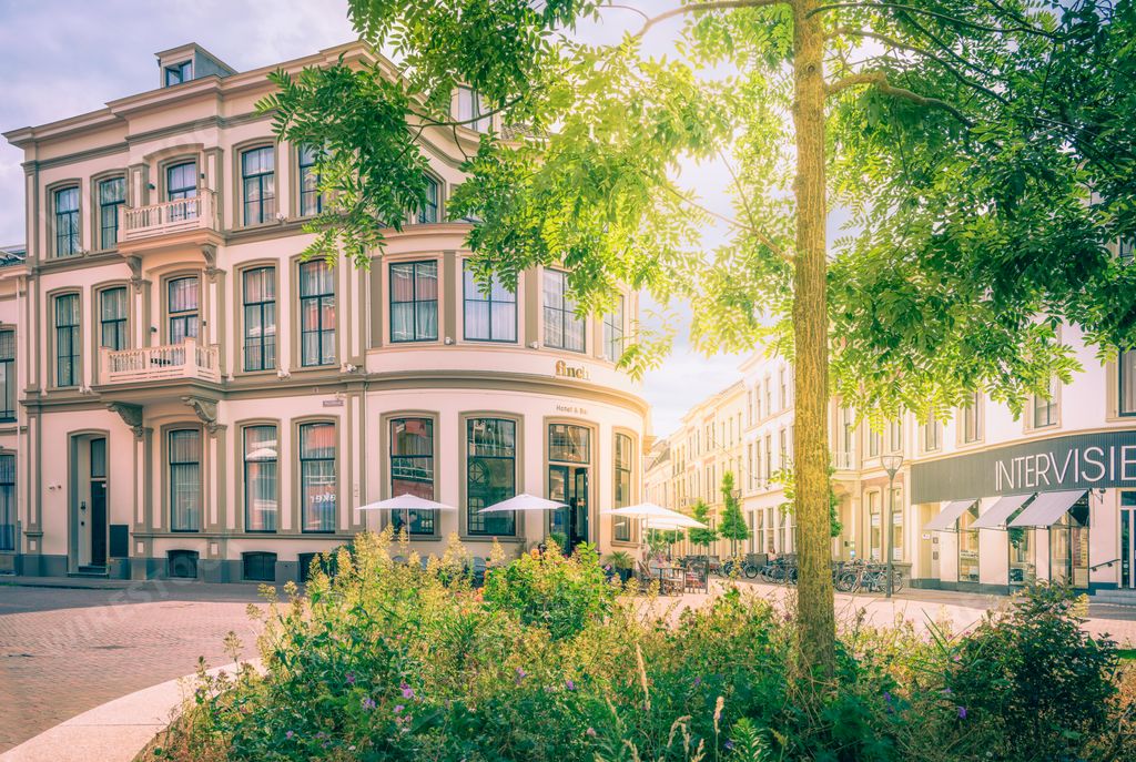 A stunning landscape of a cityscape featuring multiple buildings around an open courtyard, featuring a beautiful flower garden in the foreground