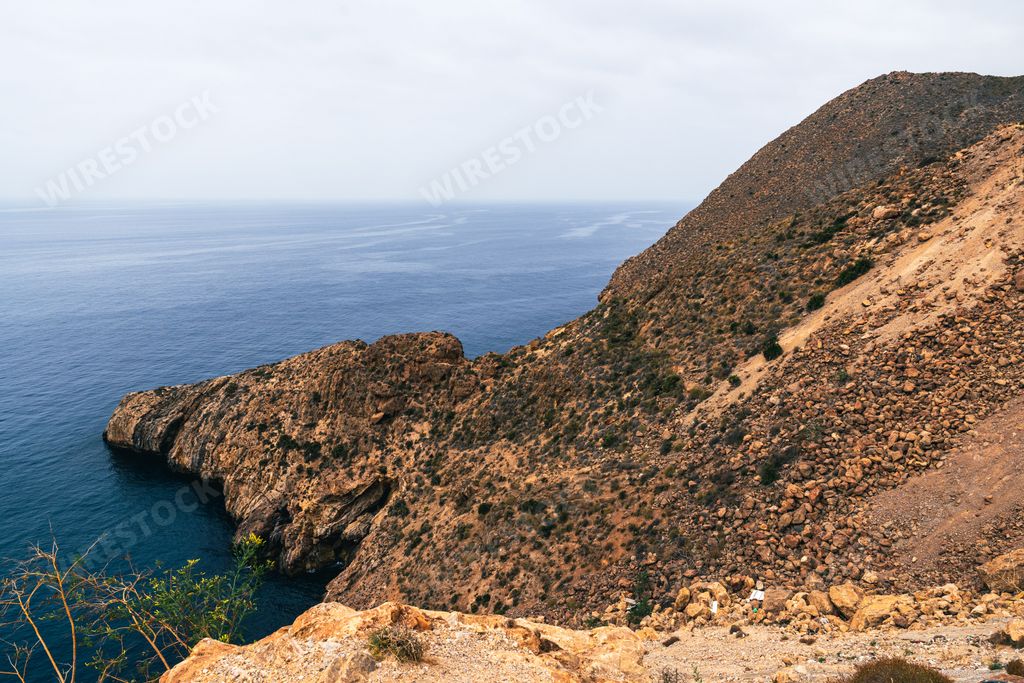 A scenic view of a rocky coastline with a vast ocean under a cloudy sky