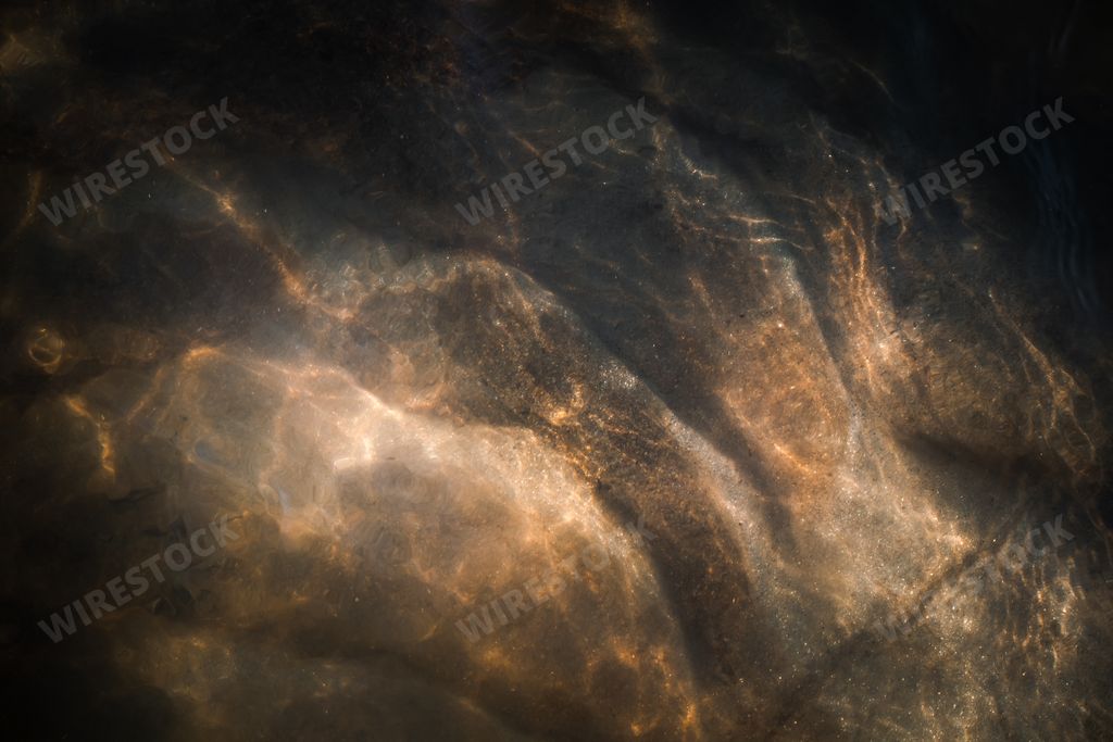 Unique art of nature - the sun shining through the water in a stream down to the ground