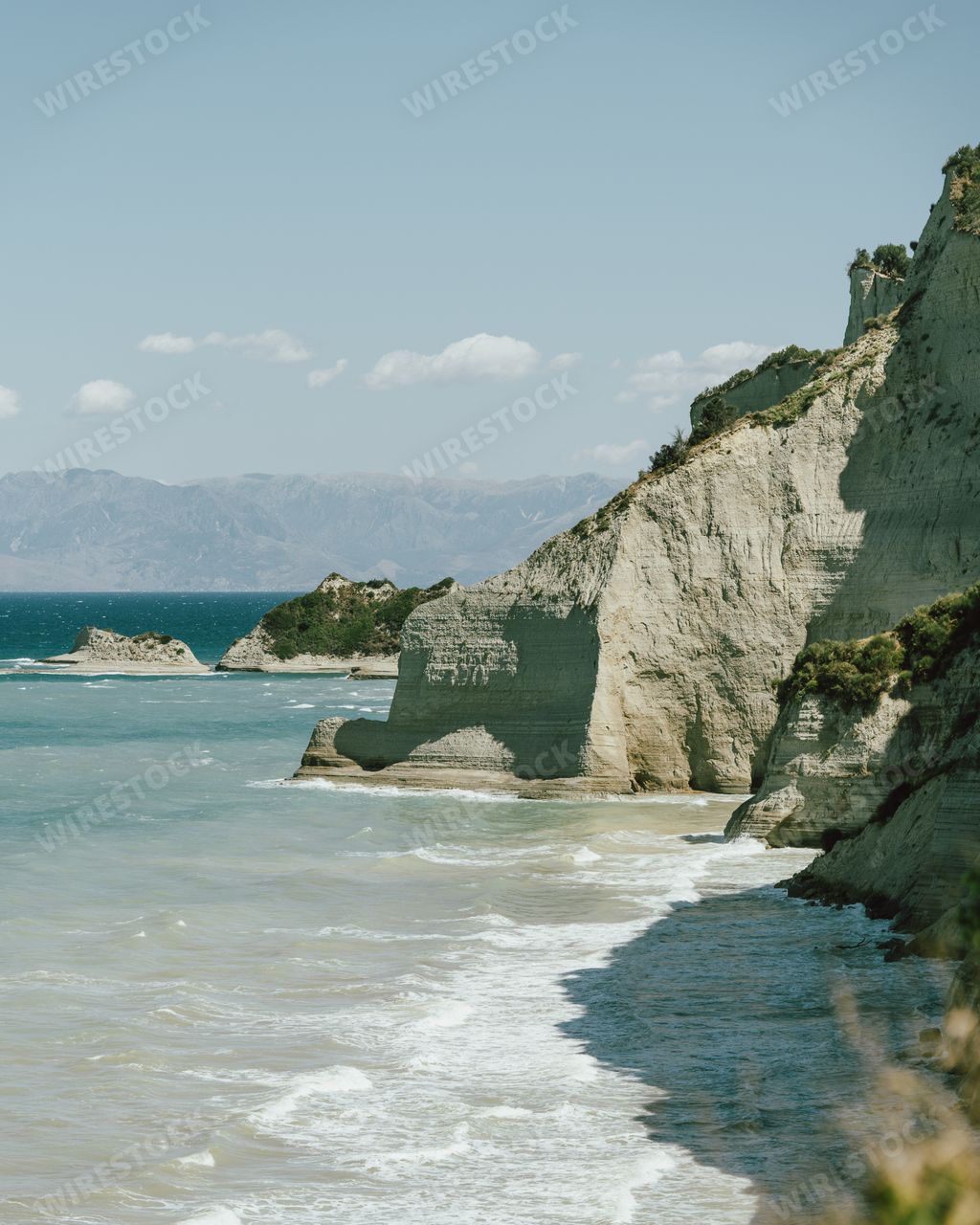 Vertical shot of cliffs covered in greenery surrounded by the sea Stock ...
