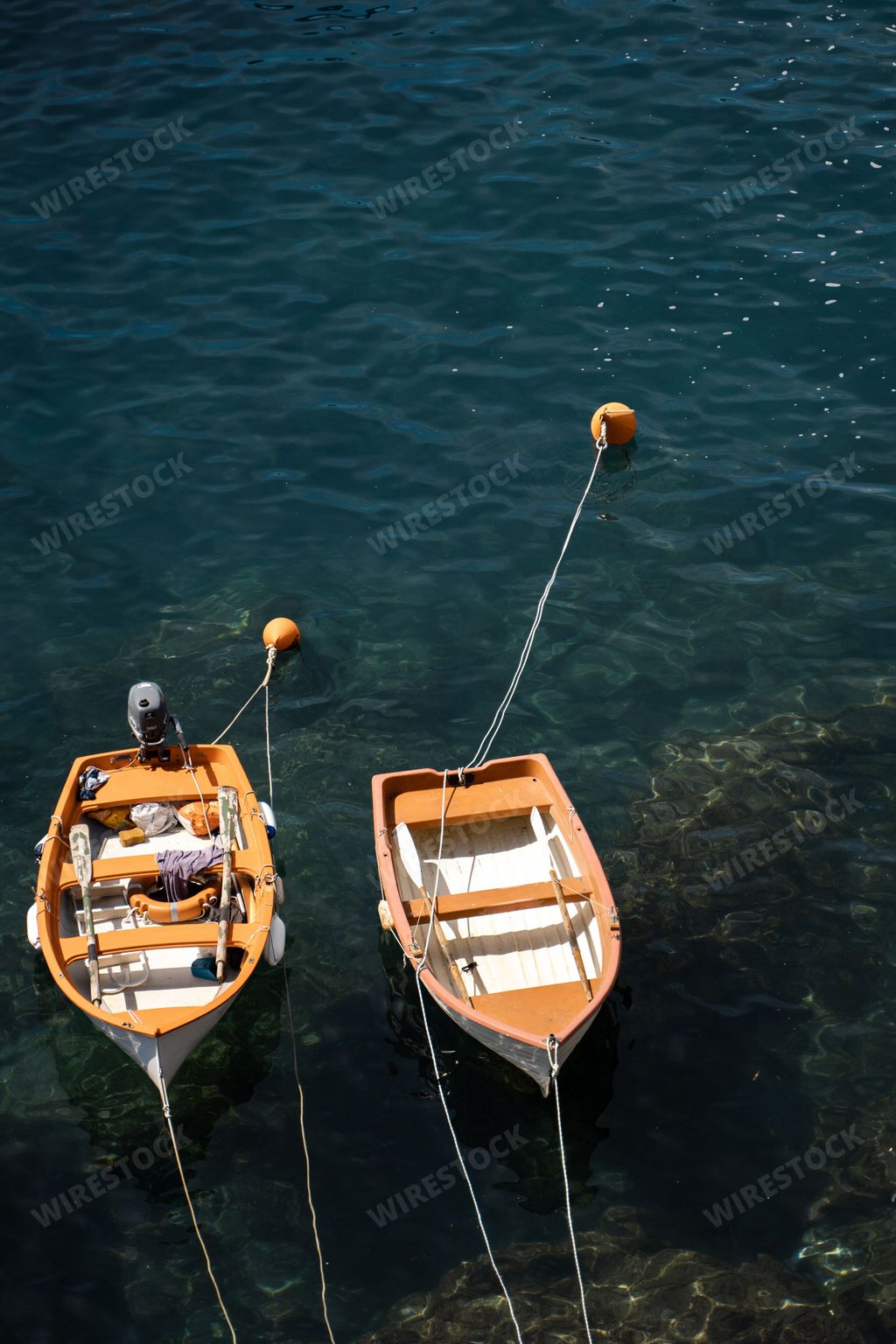 A vertical shot of two wooden boats moored on a calm rocky coast in Vernazza, Cinque Terre, Italy