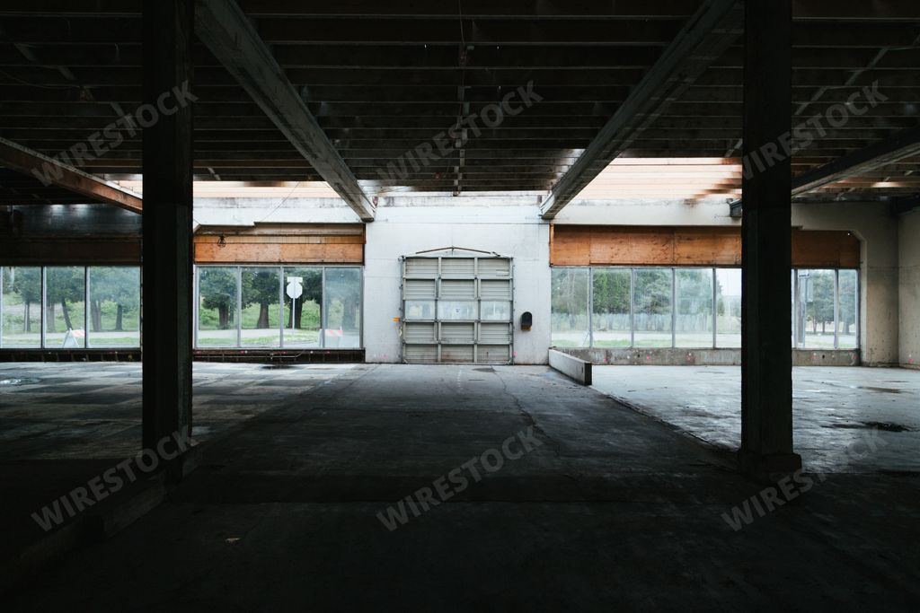 An empty abandoned room with big windows facing the garden covered in greenery