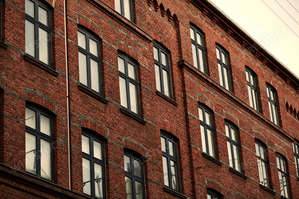A modern red stone building with large black windows under a grey sky