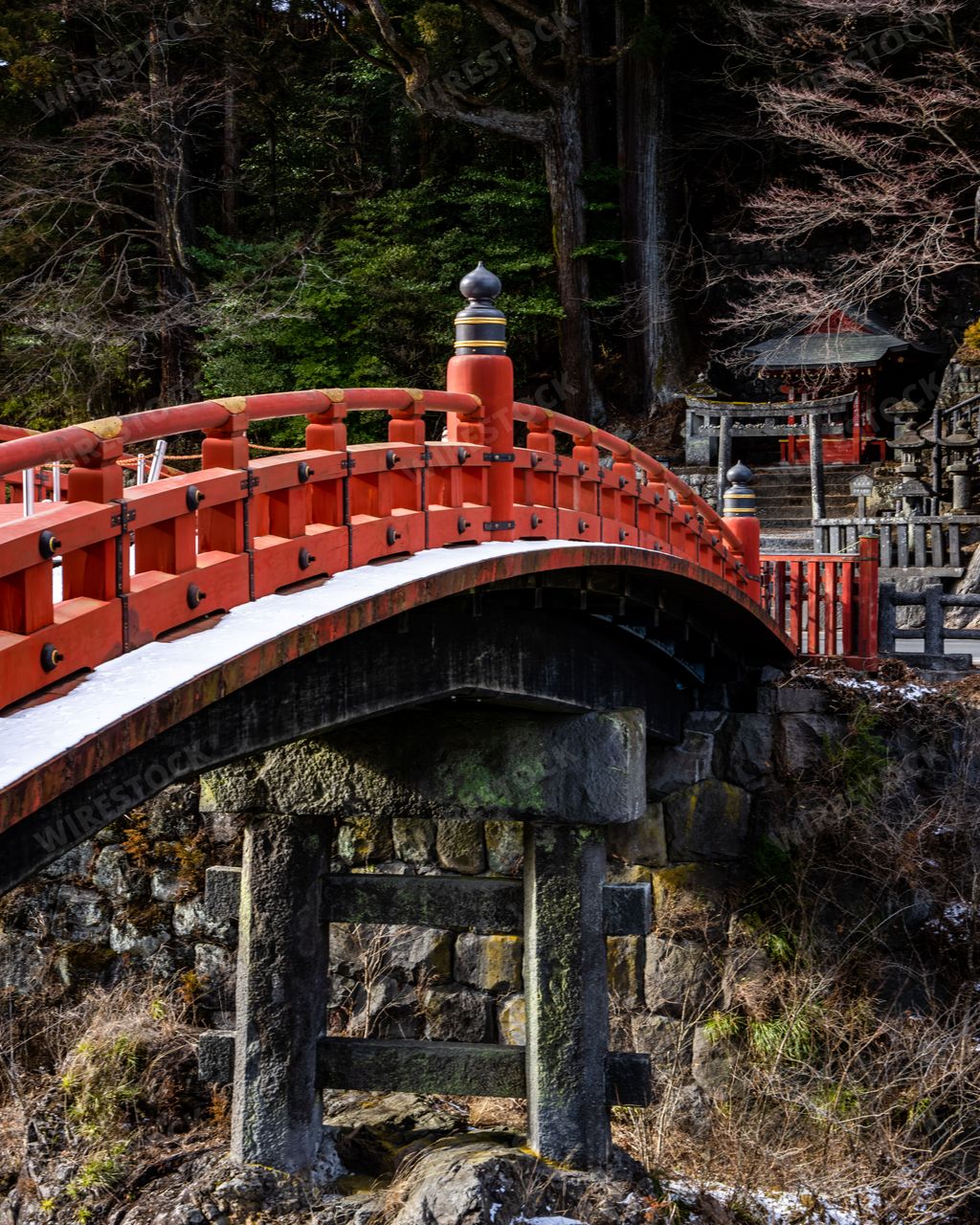 Stunning winter snow vertical shot of the romantic sacred Shinkyo bridge at the entrance to Nikko’s shrines in Nikko Japan