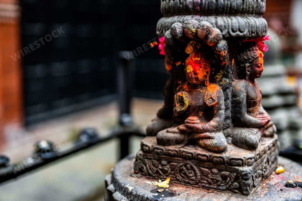 A Black Buddha idol statue with red orange yellow colored powder in Durbar Square, Nepal
