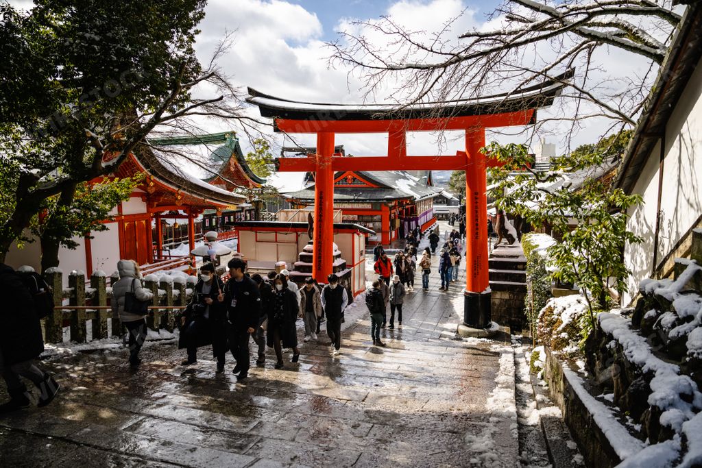 The Japanese worshipers and tourists at Ancient Japanese gateway and temples covered in rare winter snow at Fushimi Inari Shrine in Kyoto Japan.
