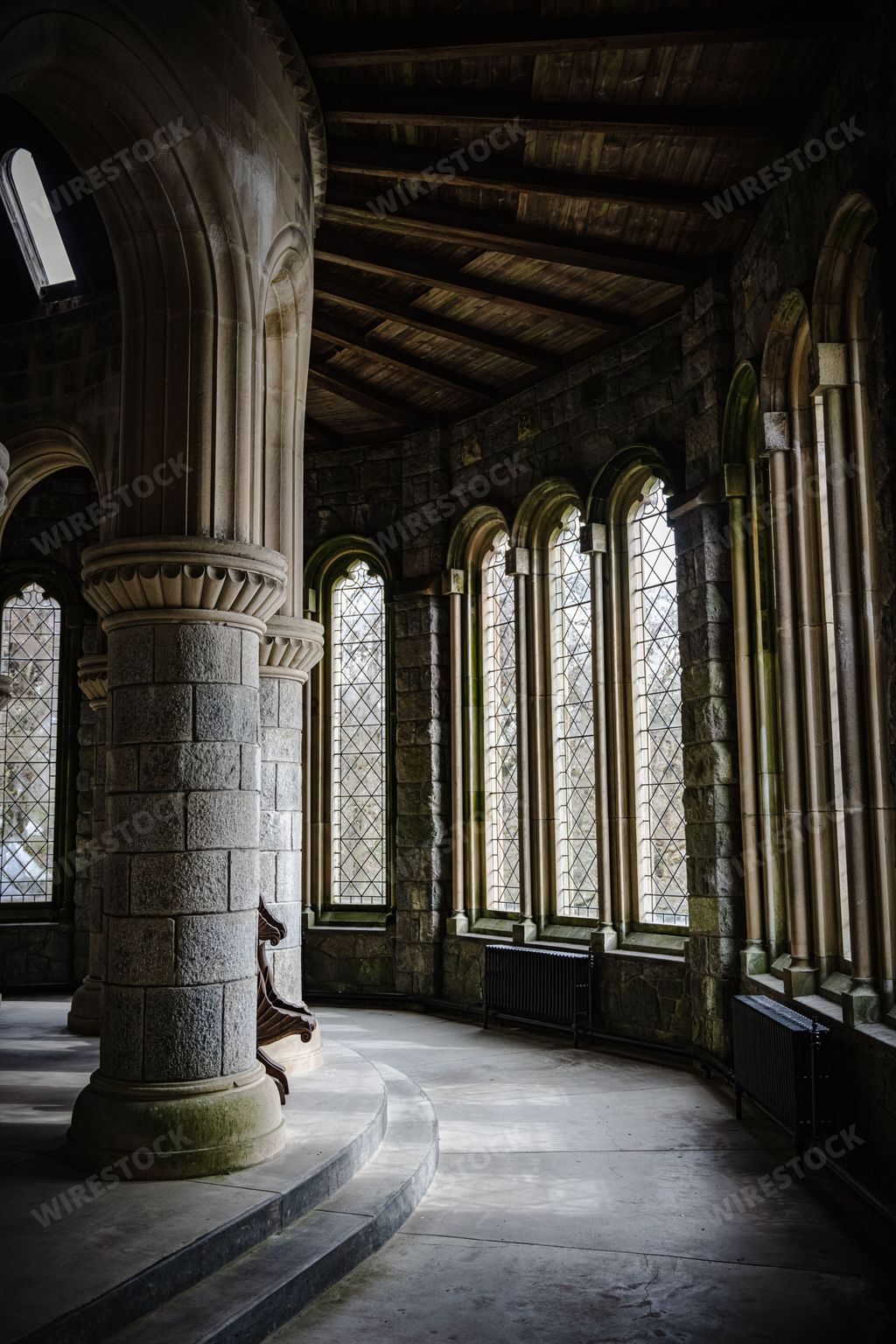 The interior of an ancient stone cathedral with pillars, arches, and large windows in Scotland, UK