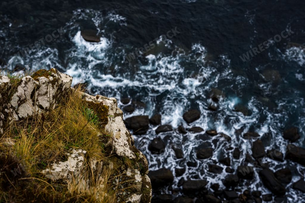 A top view of a cliff against ocean waves washing rocks at Mealt Falls on the Isle of Skye in Scotland, UK