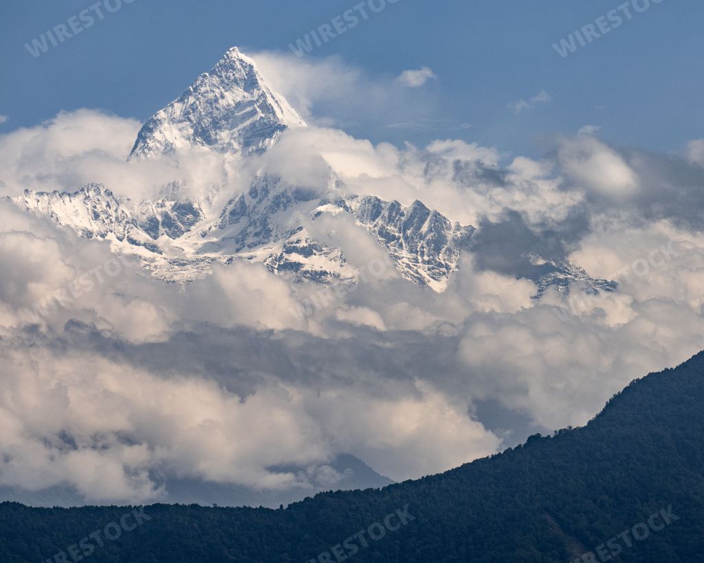 The Machapuchare AKA Fishtail Mountain snowy peak covered with clouds, Himalaya Range, Nepal.