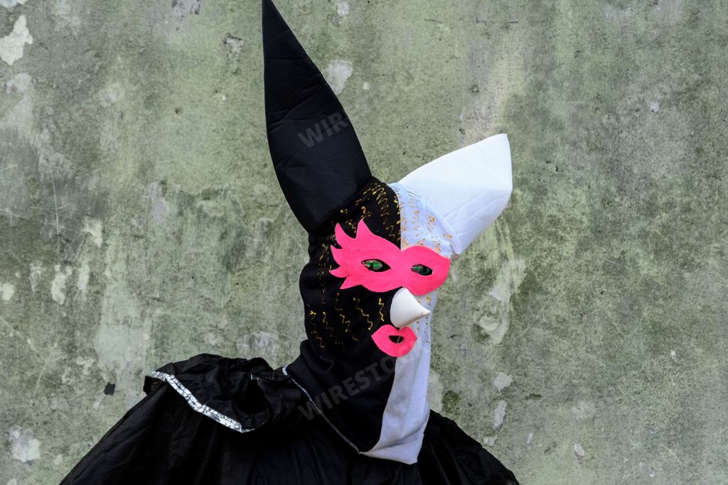 An image of a black and pink witch costume resting on a grey stone floor