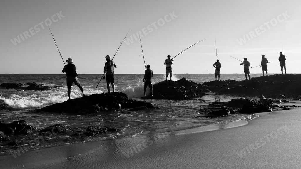 Silhouette of fishermen with their poles at sunset. Salvador, Bahia, Brasil