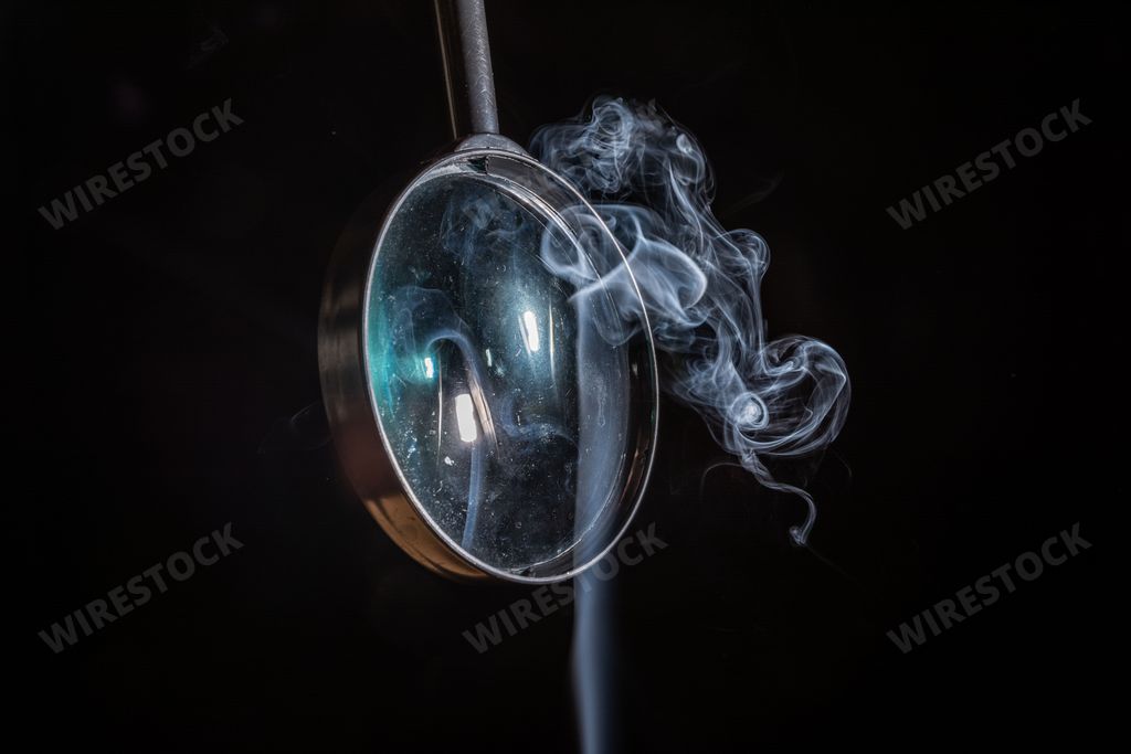 A magnifying glass with smoke on black background