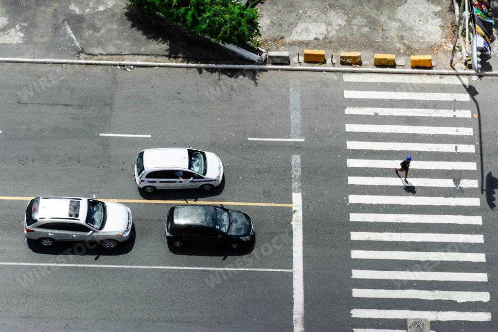 The cars waiting for the green light and a person crossing at the crosswalk in Salvador, Brazil