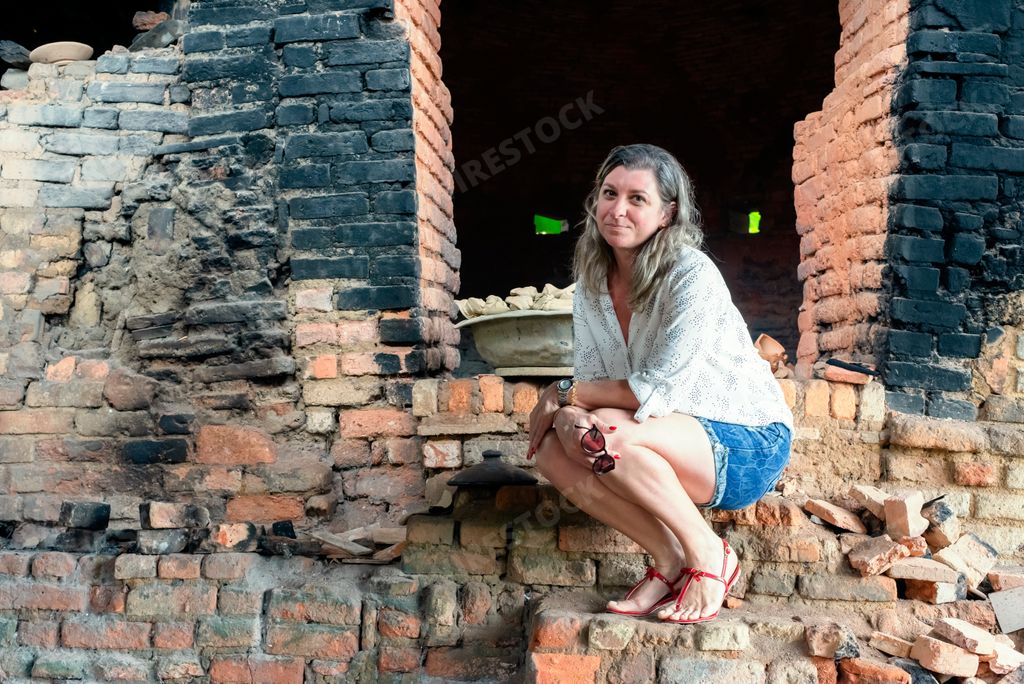 A portrait of a woman crouching in an old rustic wood-burning oven. Maragogipinho, Bahia, Brazil
