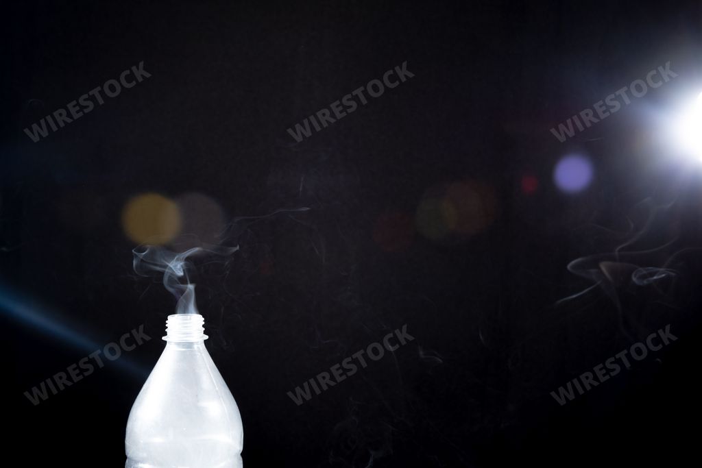 The smoke coming out of a plastic bottle on black background -  aromatherapy concept