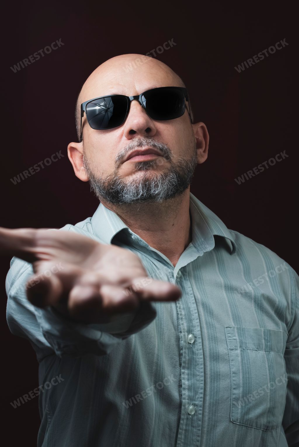 Portrait of a bearded and bald man wearing eyeglasses against a red dark background. Salvador, Bahia, Brazil.