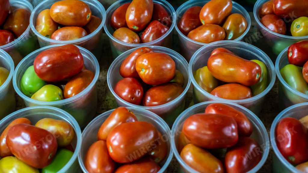 A closeup of the fresh red tomatoes in the plastic containers in the market