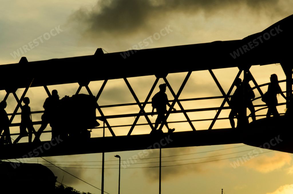 The silhouettes of people walking on a bridge at sunset in Salvador city, Bahia, Brazil