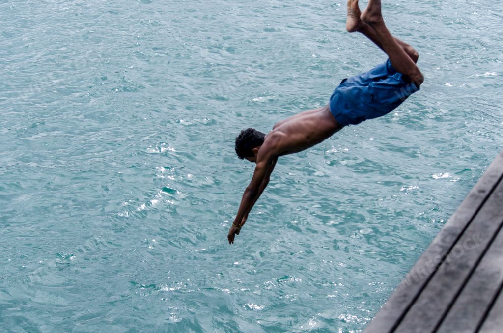 A young man jumping from the pier into the beach in Salvador, Brazil