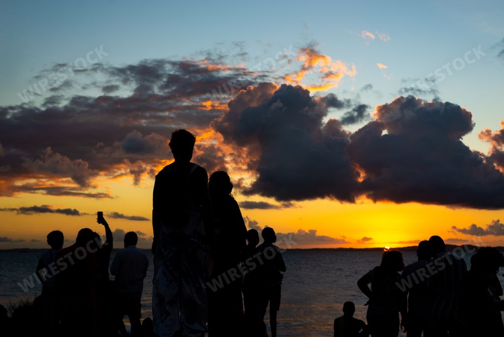 A silhouetted shot of people on the beach with Dramatic sunset sky in the city of Salvador, Brazil.