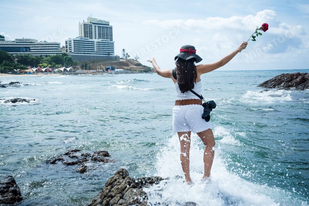 A young female standing in the ocean with her arms extended outwards