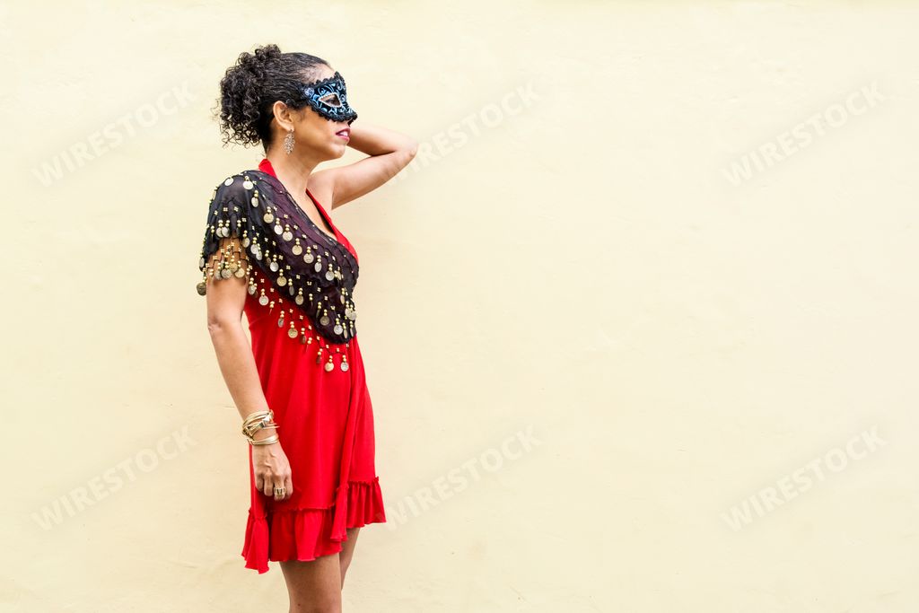A Brazilian woman wearing Venice Carnival mask against a wall background in Brazil