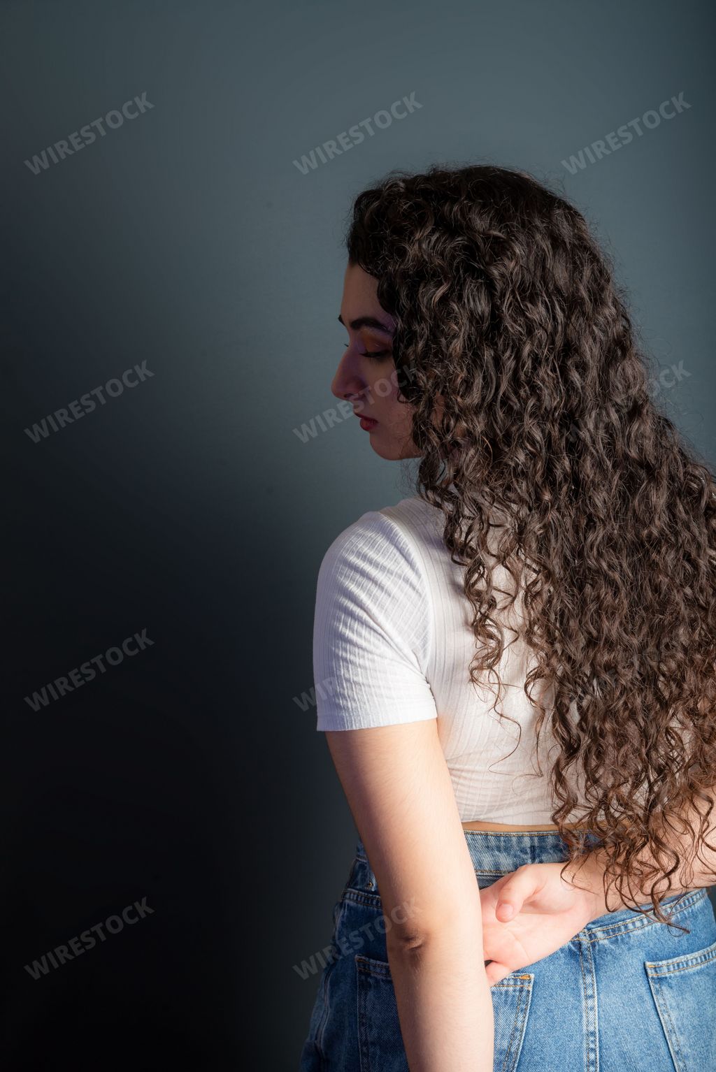 Profile of beautiful young woman with black hair wearing white shirt. Against gray background. 