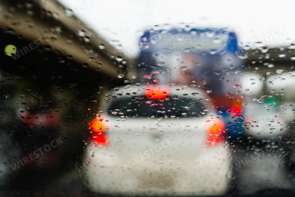 Car traffic on streets through car window with rain water drops. Salvador, Bahia, Brazil.