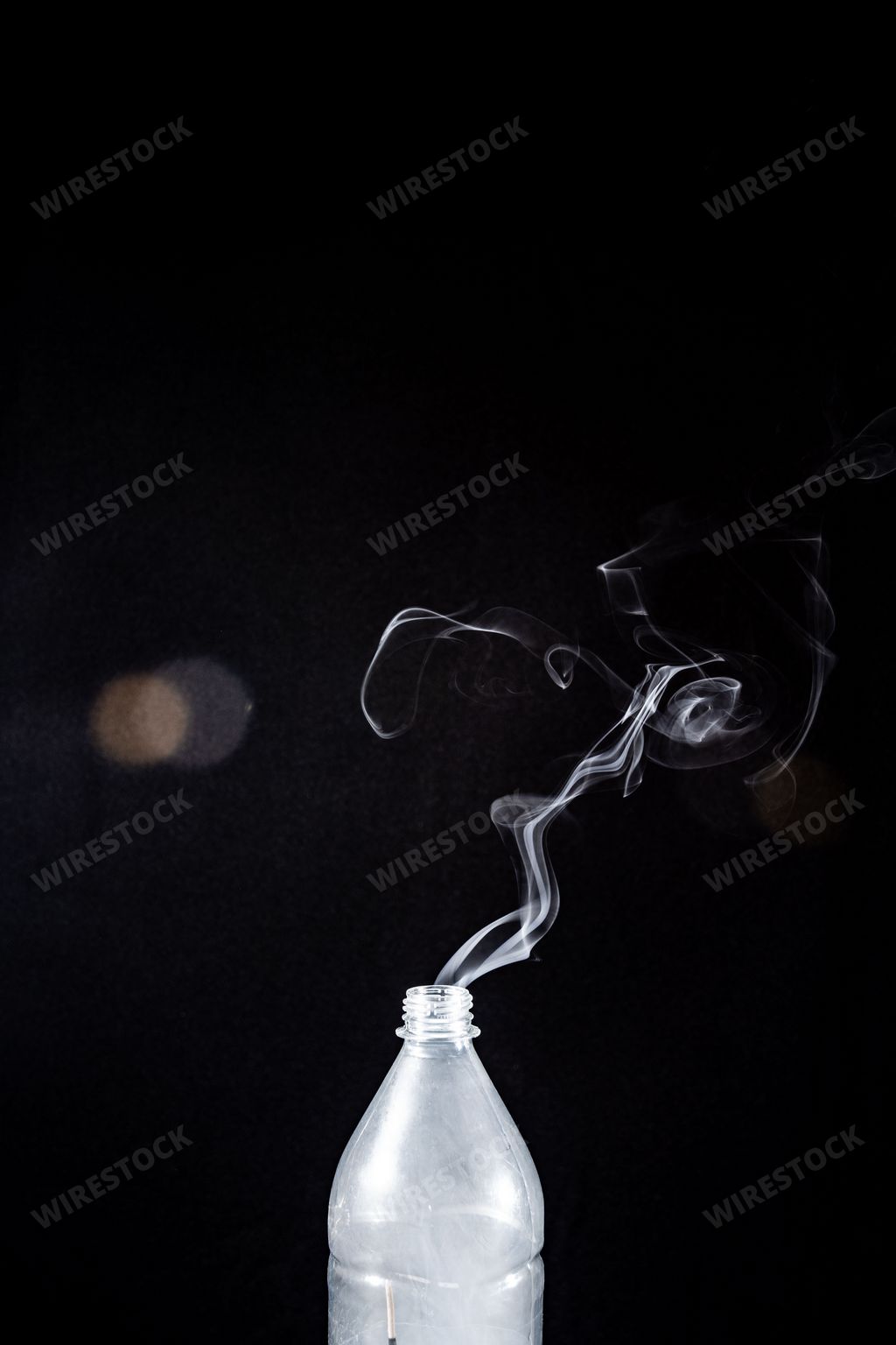 The smoke coming out of a plastic bottle on black background -  aromatherapy concept